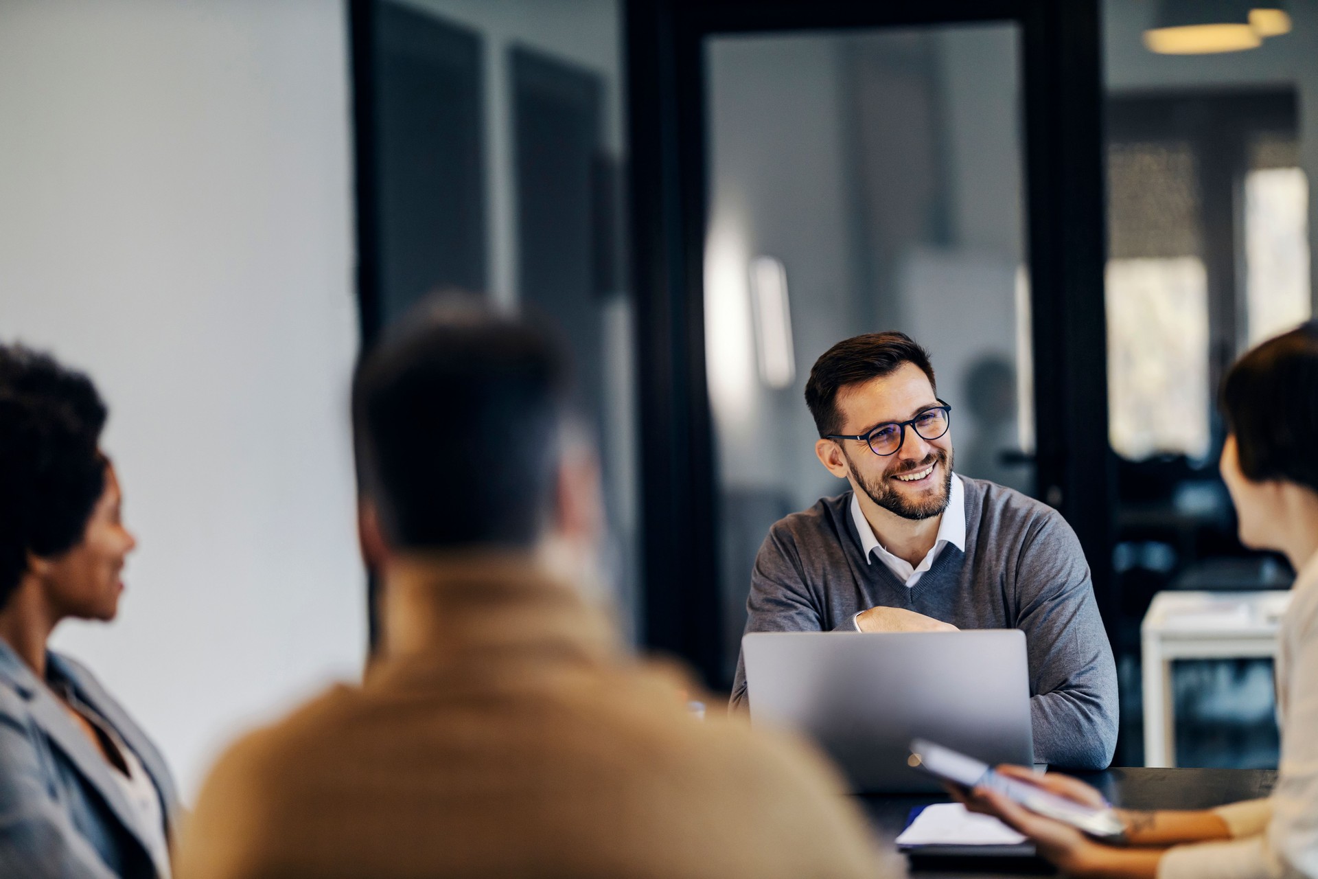 Un homme d’affaires heureux est assis dans l’espace de co-working avec des collègues et a un briefing.